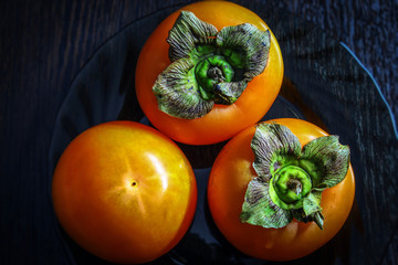 Top view of a fresh juicy fruit called persimmon. Persimmon is on a plate