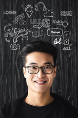 smiling asian man in glasses looking at camera on wooden background with illustration