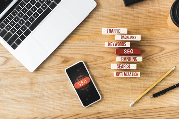 top view of wooden rectangles with illustration of concept words of seo, smartphone, laptop, pen...