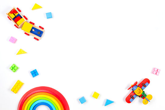 Baby kids toys background. Wooden train, constructor airplane, stacking toy rainbow, plane and colorful blocks on white background. Top view, flat lay