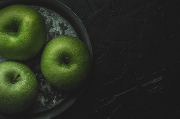 Fresh green apples wet on a black background. Food Concept