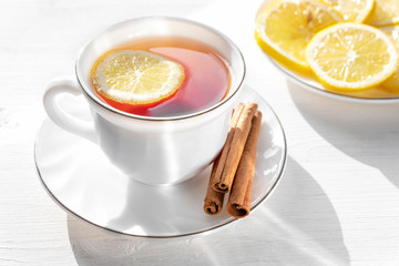 Tea in a white Cup with lemon slices and cinnamon.