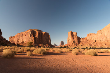 A sunset view of the arid lands in Monument Valley with the mesas at the back