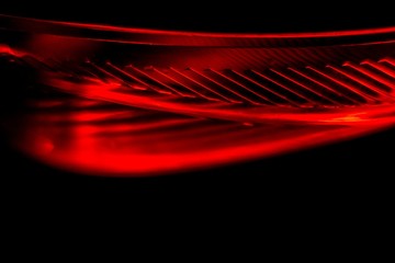 Abstract red and black background showing a detail of a rear red tail light of a modern car