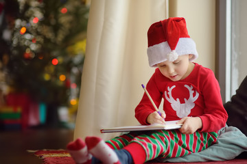 Little boy writing the letter to Santa. Child dreams of a gift that he can receive.