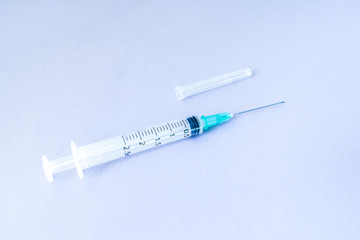 syringe, syringe with needle attached and with the needle cap on the side on white isolated background.