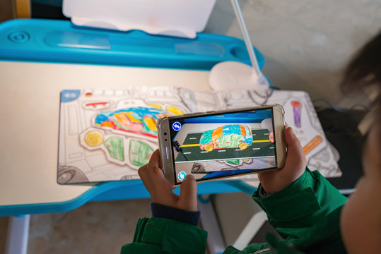 Zhongshan,China-February 8, 2018:kid playing Augmented Reality popup paintings of a color filled car and road via mobile. AR and VR games become more and more popular.