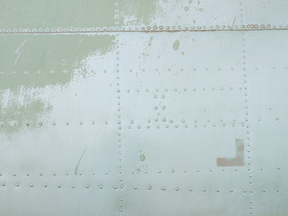 Old green metal surface of the aircraft fuselage with rivets