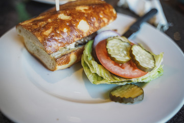 Burger with french bread  and vegetables on white plate on cafe