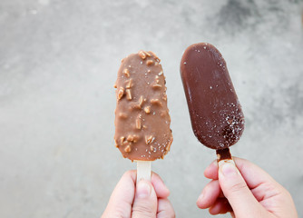 Hands holding vanilla icecreams covered with chocolate and almonds