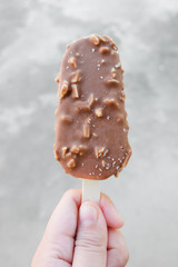 Hands holding vanilla icecreams covered with chocolate and almonds