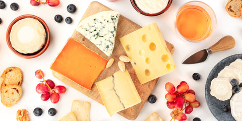 An assortment of cheeses panorama, shot from above on a white background. Blue cheese, soft cheese...