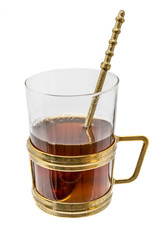 Glass with metal handle and spoon of bronze filled with hot tea
