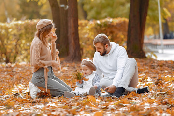 Family in a autumn park. Woman in a brown sweater. Cute newborn little girl with parents