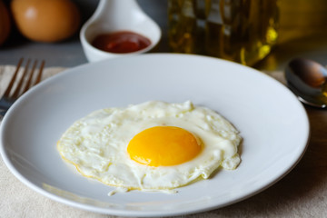 Close up  fried egg is in a white round dish placed