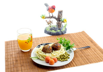 Children's meal - pasta with meatballs and fruit juice on the table close-up