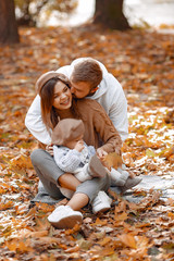 Family in a autumn park. Woman in a brown sweater. Cute newborn little girl with parents