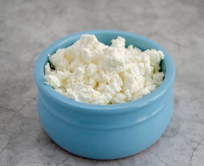Cottage cheese in blue glass stands on a wooden table. Healthy breakfast. Close-up