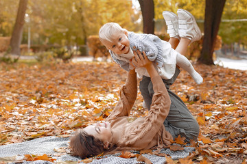 Fashionable mother with daughter. Family in a autumn park. Little girl in a brown hat