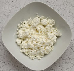 Cottage cheese in a plate, milk in a bottle on a wooden table and a napkin. Healthy breakfast