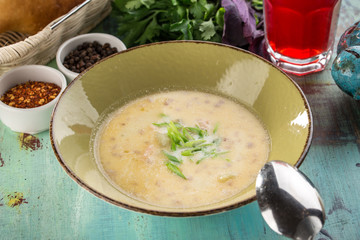 homemade vegetable soup with green onion in green bowl on blue wooden table