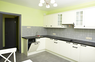 New white small kitchen in a room with green walls.