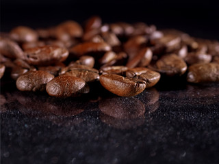 Сoffee grains close on a black shiny background. Macro. Food concept