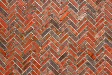 Rough industrial reddish herringbone brick wall background texture