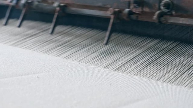 White fabric sewn on a machine at a textile factory. Industrial Textiles Production Line.