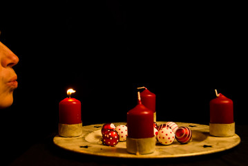 A woman blows out the red candles of an advent wreath in Christmas time1. Advent