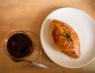 Glass of black tea and traditional turkish pie (borek) with black indian sesame seeds