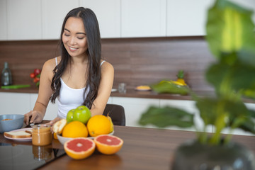 Smiling lovely Asian female preparing her breakfast