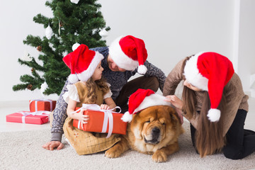 Pet, holidays and festive concept - Family with dog are lying on floor near christmas tree.