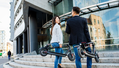 Two business people with electric scooter talking outside in front of modern business building. © Zoran Zeremski