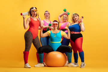 Young caucasian plus size female models training on yellow background. Copyspace. Concept of sport,...
