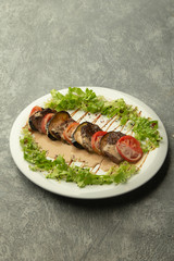 beef slices served in row with aubergine and tomato garnished with sauce