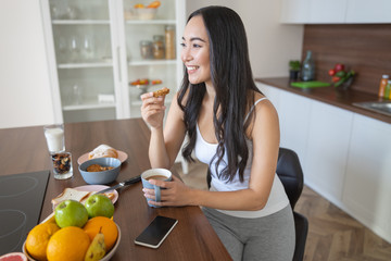 Joyful girl eating biscuits in the kitchen