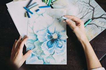 beautiful girl draws with pastel crayons on a window background