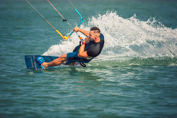 Professional kiter makes the difficult trick on a river. Kitesurfing Kiteboarding action photos man among waves quickly goes