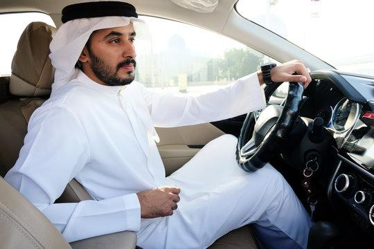 Driving Arab man holding steering wheels wearing kandura dish dash