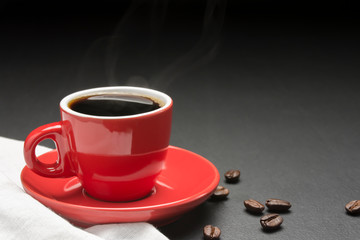 Black coffee, hot needle, hot vapor in a red coffee cup And there is a roasted coffee bean on the black table