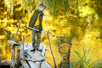 Kid fishing in a river, sitting on a wood pontoon