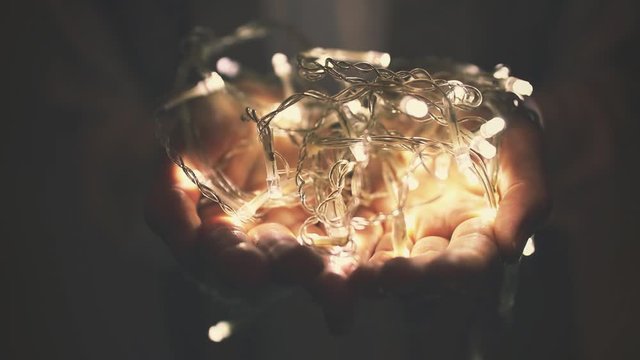 christmas miracle - woman holds glowing led light garland in hands