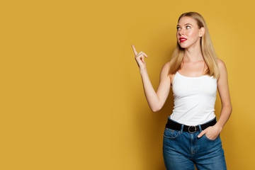 Young pretty woman pointing up on bright yellow background