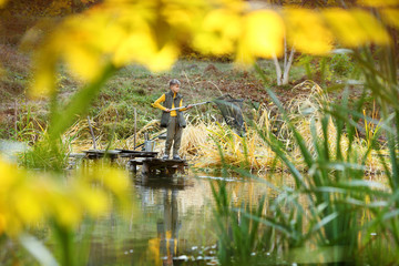 Boy with a fishing net is leaning on a wooden dock railing
