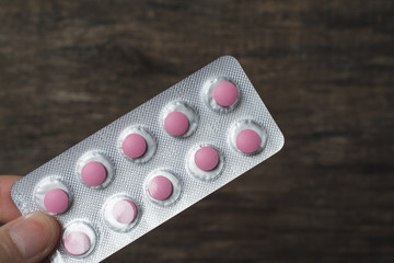 Pink pills blister hand holding