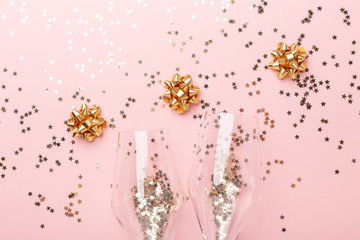 Christmas flat lay. Champagne glasses and gold decoration on pink background - Image