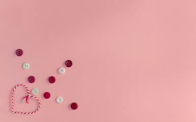 Composition for Valentine's Day February 14th. Heart and buttons decor on a pink background. Greeting card. Flat lay, top view, copy space.