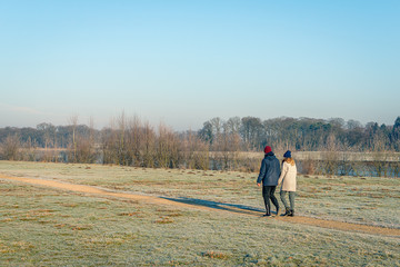 Man and woman walk hand in hand in a winter landscape