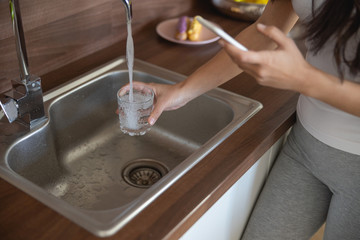 Lady drawing fresh water from the faucet